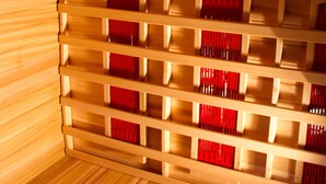 En sauna med trævægge og -bænke, udstyret med et kontrolpanel og et lys i loftet.