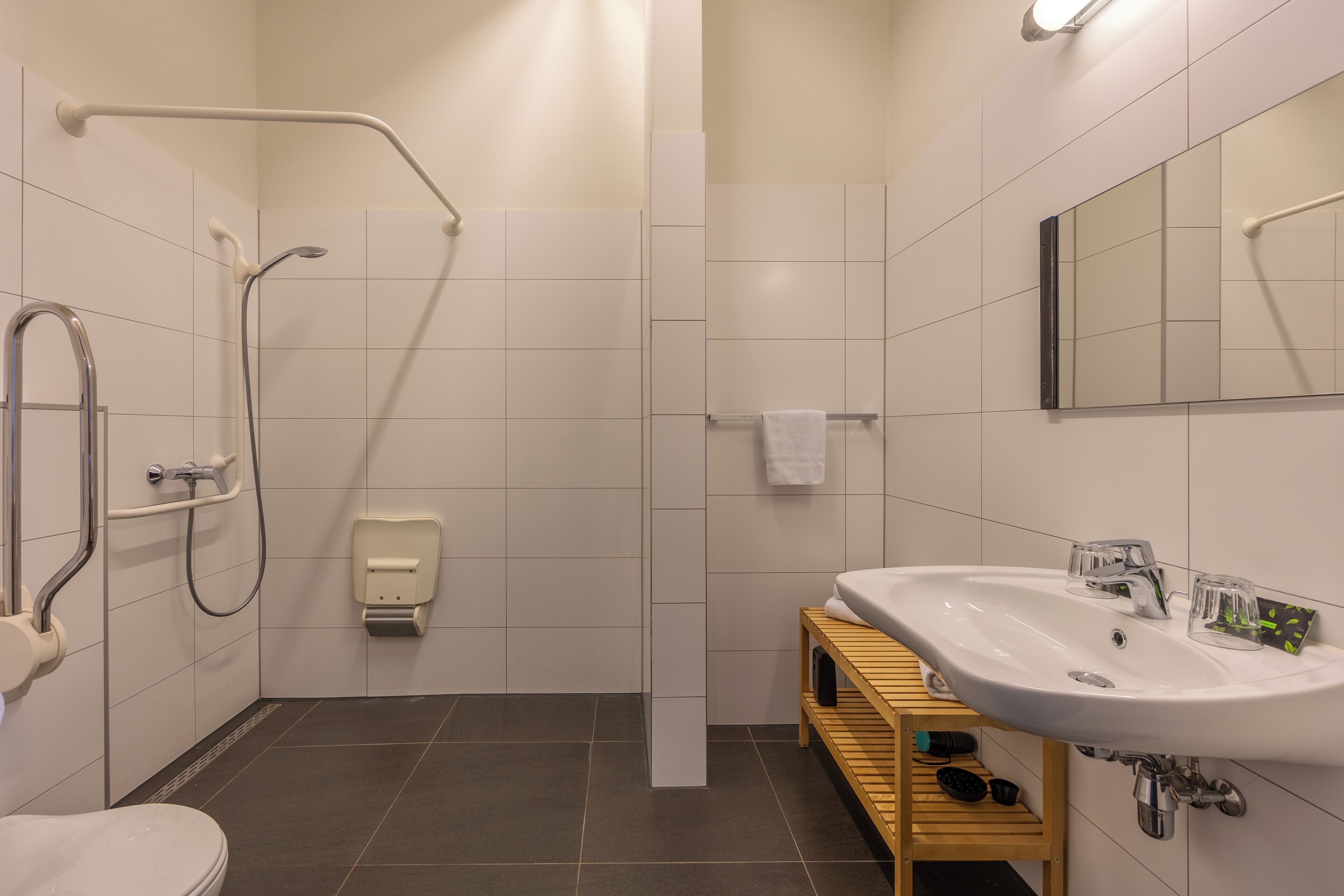 A modern bathroom with a shower, toilet, sink, and a mirror.