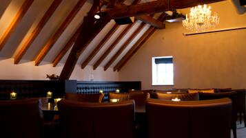 An interior with wooden beams, a chandelier, and seating.