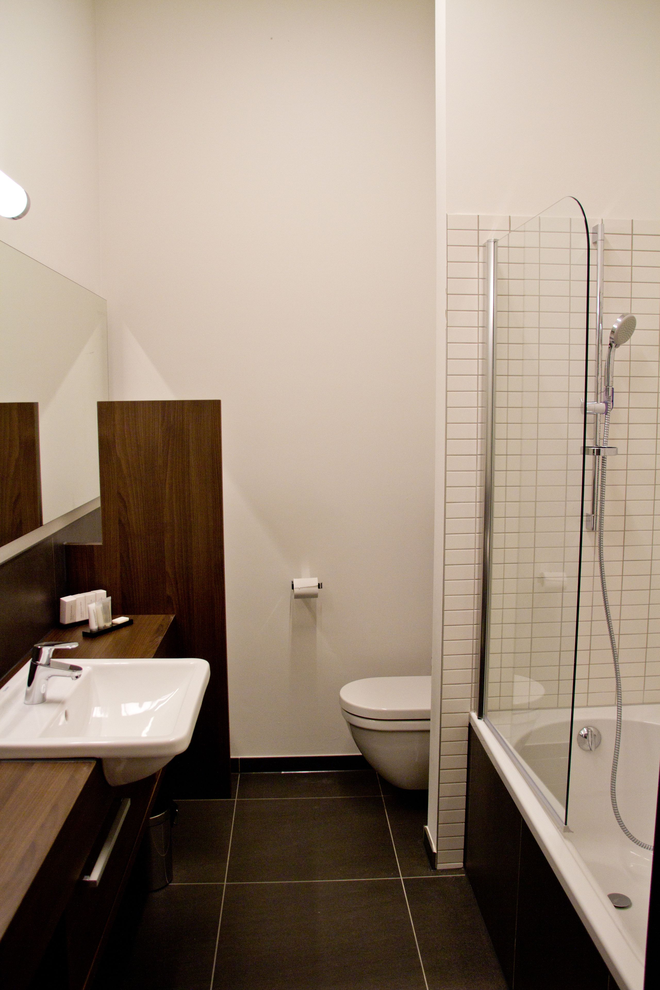 Un baño moderno con ducha de vidrio, lavamanos blanco y un inodoro.