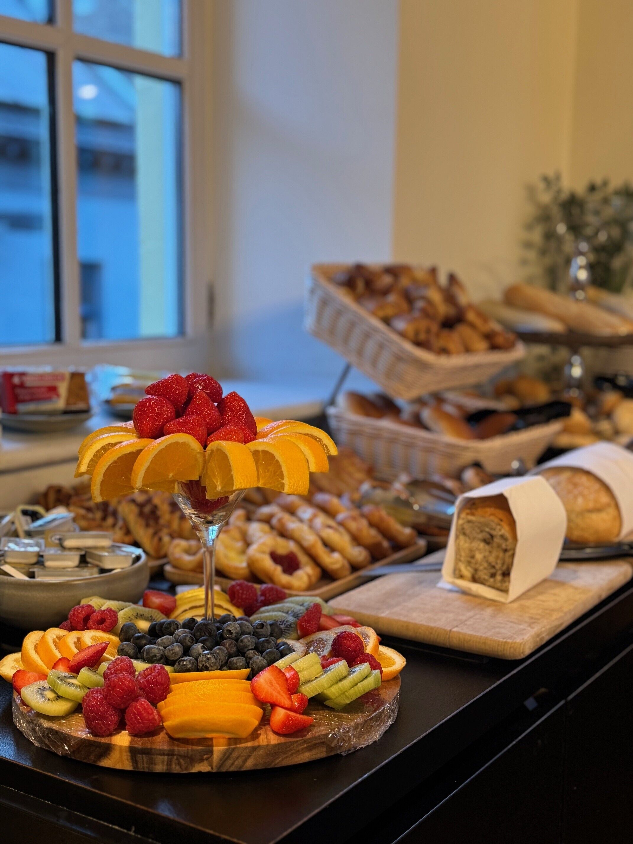 Un bufé con diversas frutas y pasteles.