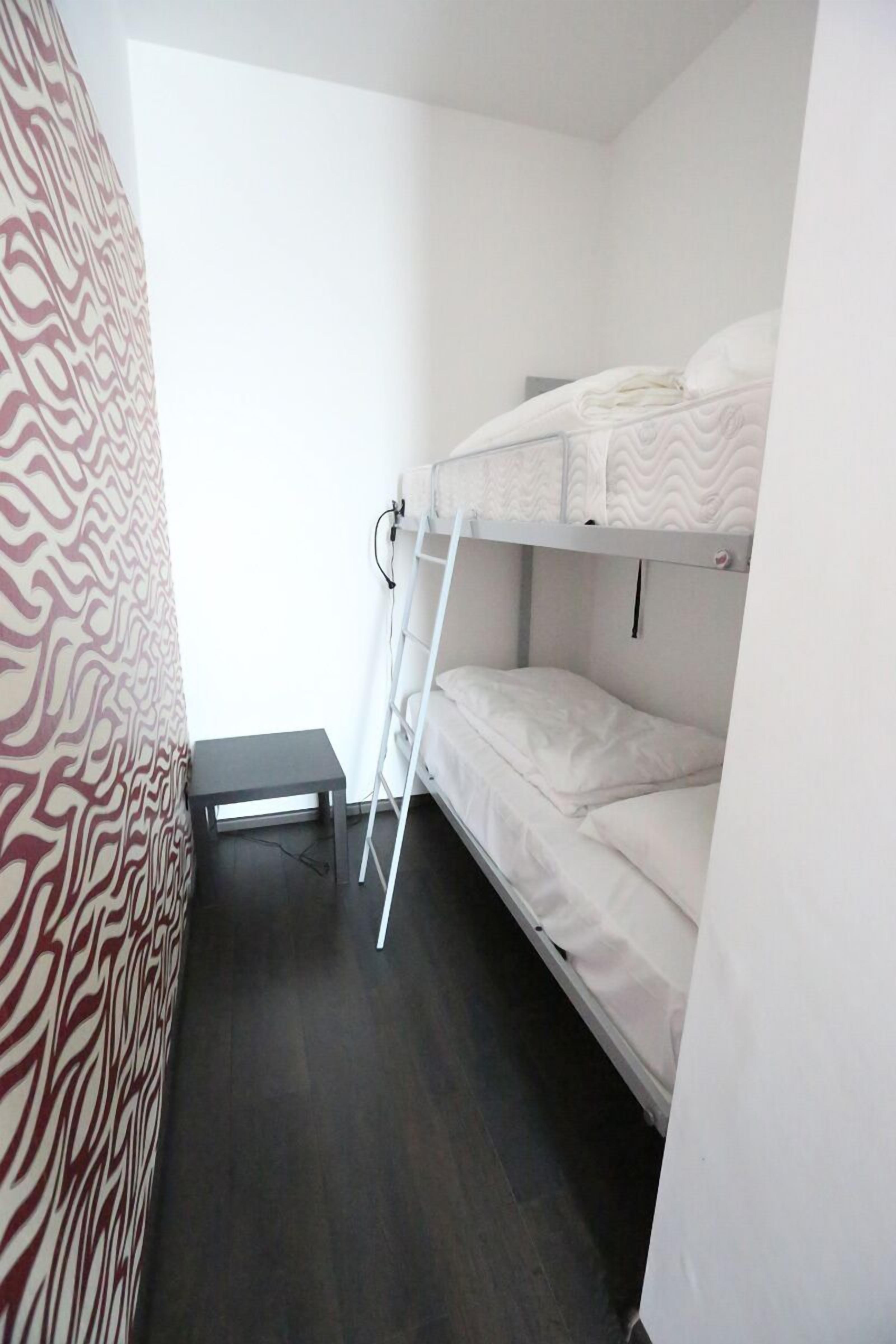 A bunk bed room with a ladder, a small table, and a patterned curtain.