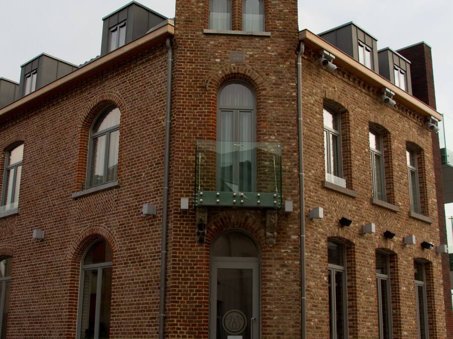 A brick building with a prominent arched entrance and a balcony.