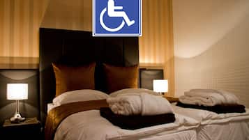 Habitación de hotel con una cama grande, dos mesitas de noche y señal de accesibilidad para sillas de ruedas.