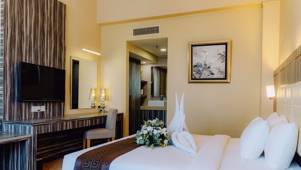Una habitación de hotel con una cama, un escritorio, una silla, un televisor y un cuadro en la pared.
