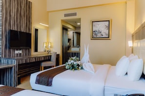 A hotel room with a bed, a desk, a chair, a television, and a framed picture on the wall.