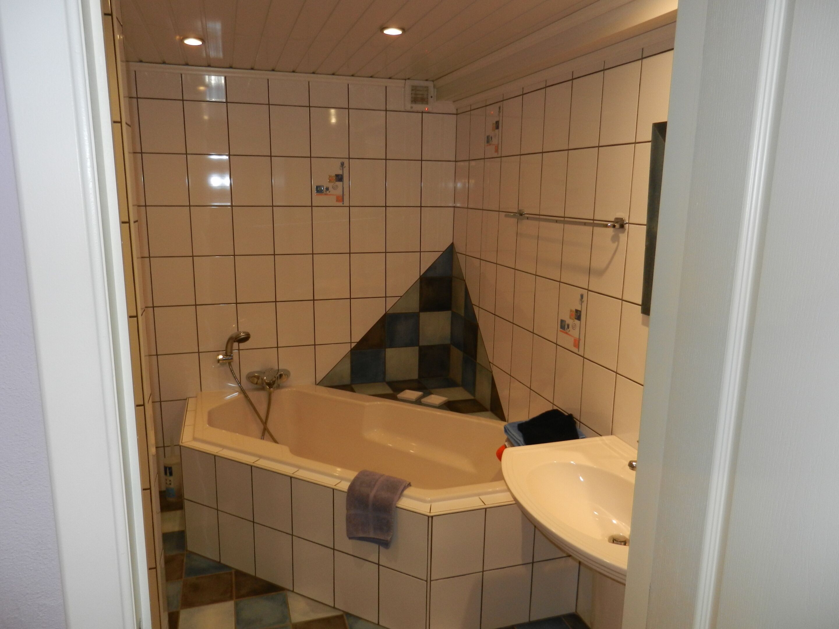 A bathroom with a bathtub, a sink, and a mirror.