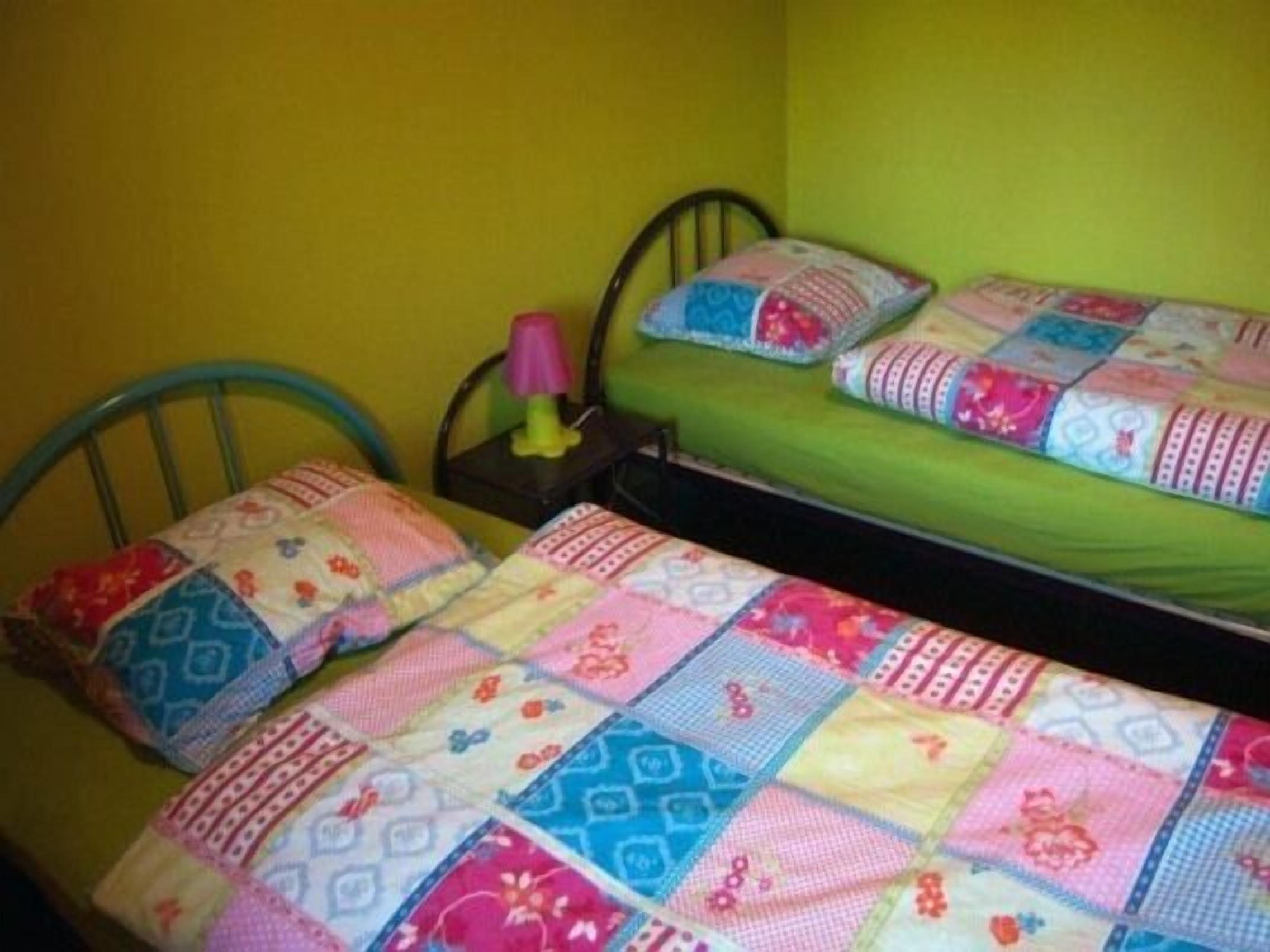 Una habitación pequeña con cama individual, colchón verde y colcha colorida.