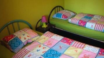 Una habitación pequeña con cama individual, colchón verde y colcha colorida.