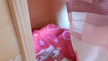 Una habitación pequeña y cerrada con una colcha rosa y un cabecero de madera.