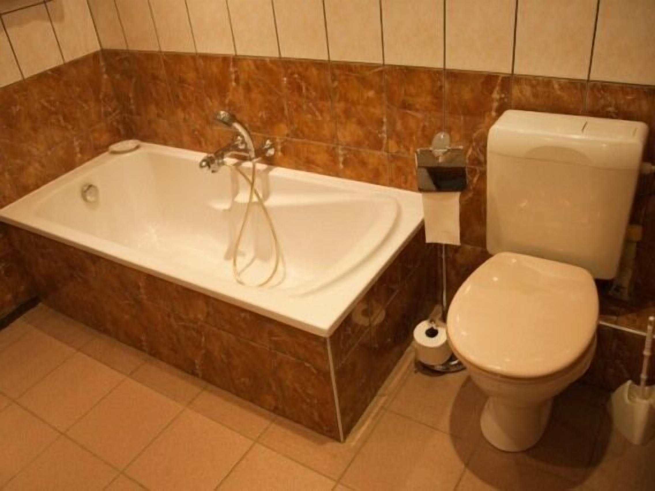 Een badkamer met een bad, toilet en toiletpapierhouder.