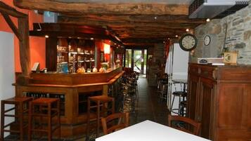 A rustic bar area with wooden furniture and a stone wall.
