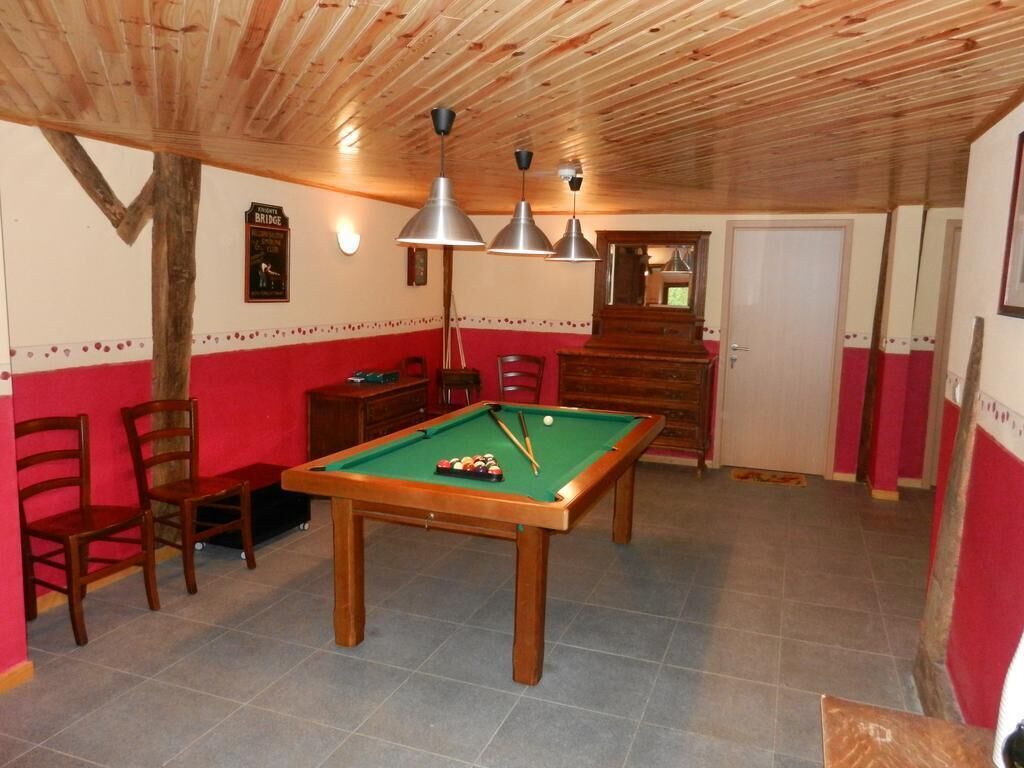 A room with a pool table, chairs, wooden ceiling, and a door.