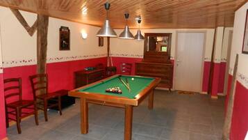 A room with a pool table, chairs, wooden ceiling, and a door.