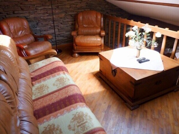 Una sala de estar acogedora con un banco de madera, un sillón de cuero y un sofá estampado.