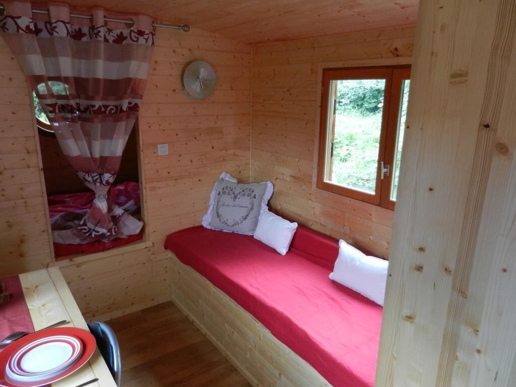 Een houten kamer met een bed, een raam en een klok aan de muur.