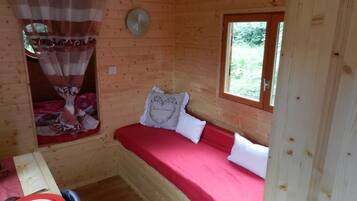 Een houten kamer met een bed, een raam en een klok aan de muur.