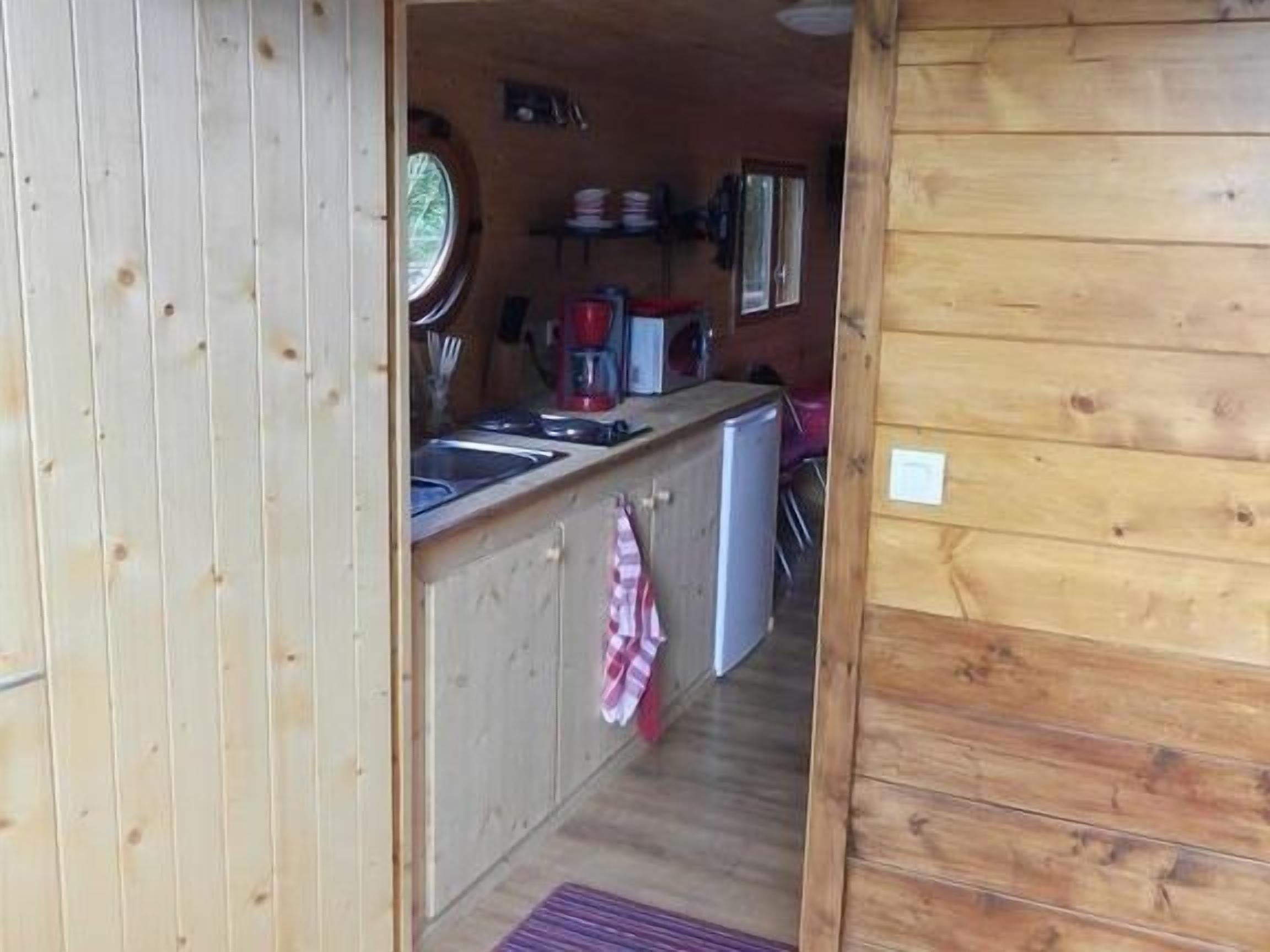 A wooden cabin interior with a kitchen area featuring a sink, a coffee maker, and a refrigerator.