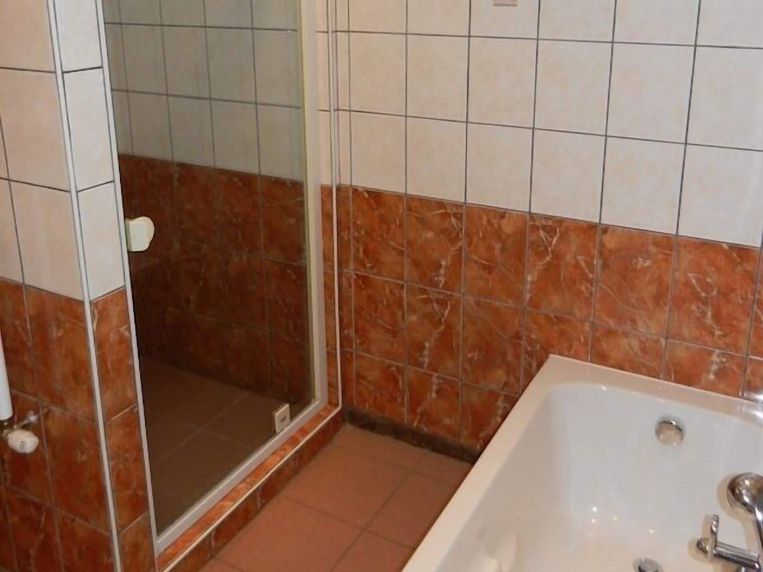 Un baño con ducha, bañera y paredes de azulejos.