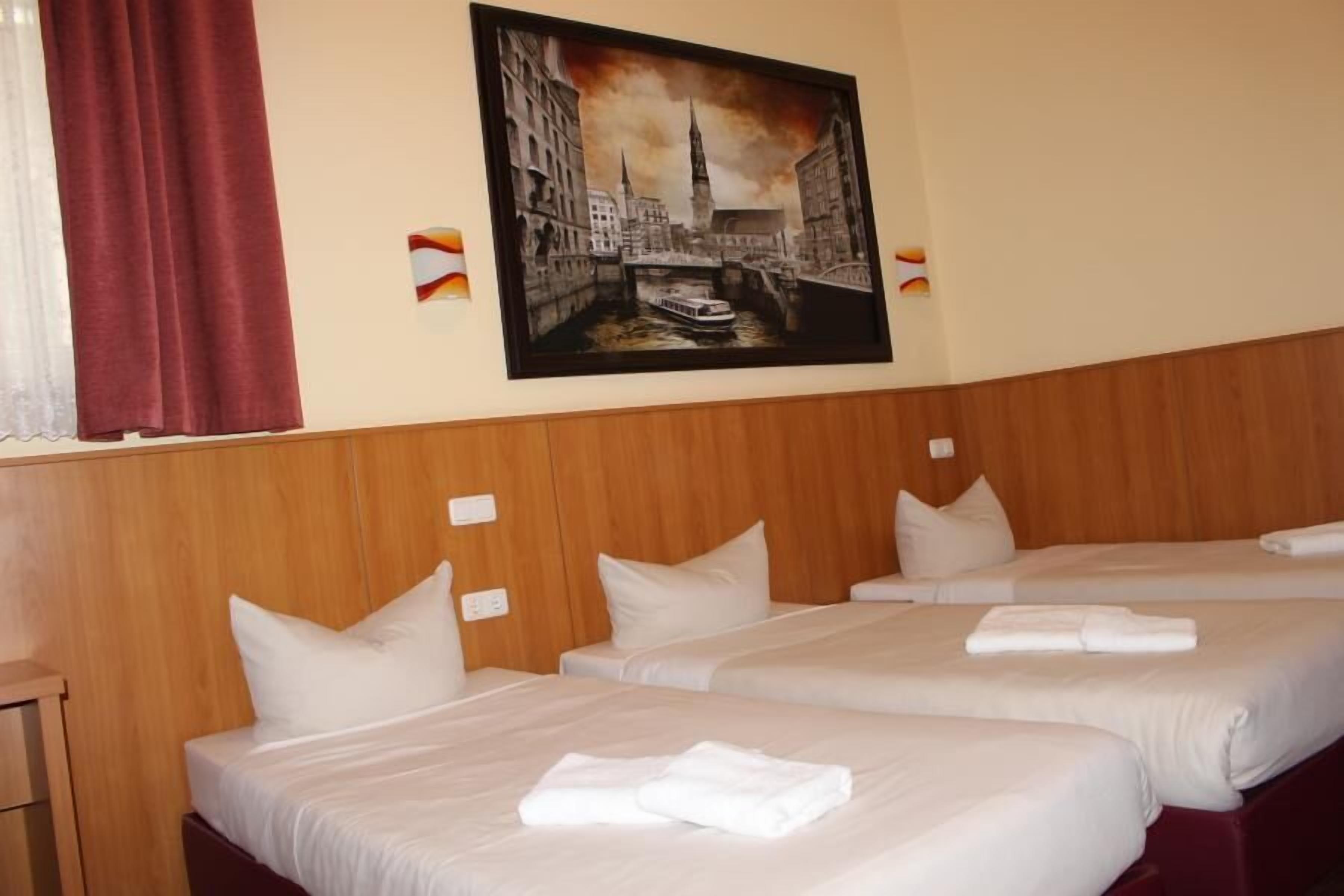 Een hotelkamer met drie bedden, een houten hoofdbord en een stadslandschap op de muur.