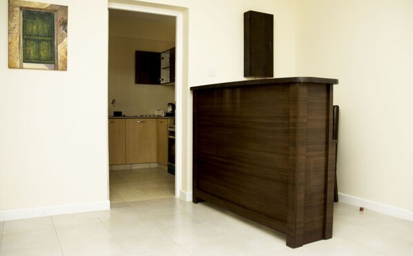 A kitchen with wooden cabinets, a dark wooden counter, and a tiled floor.