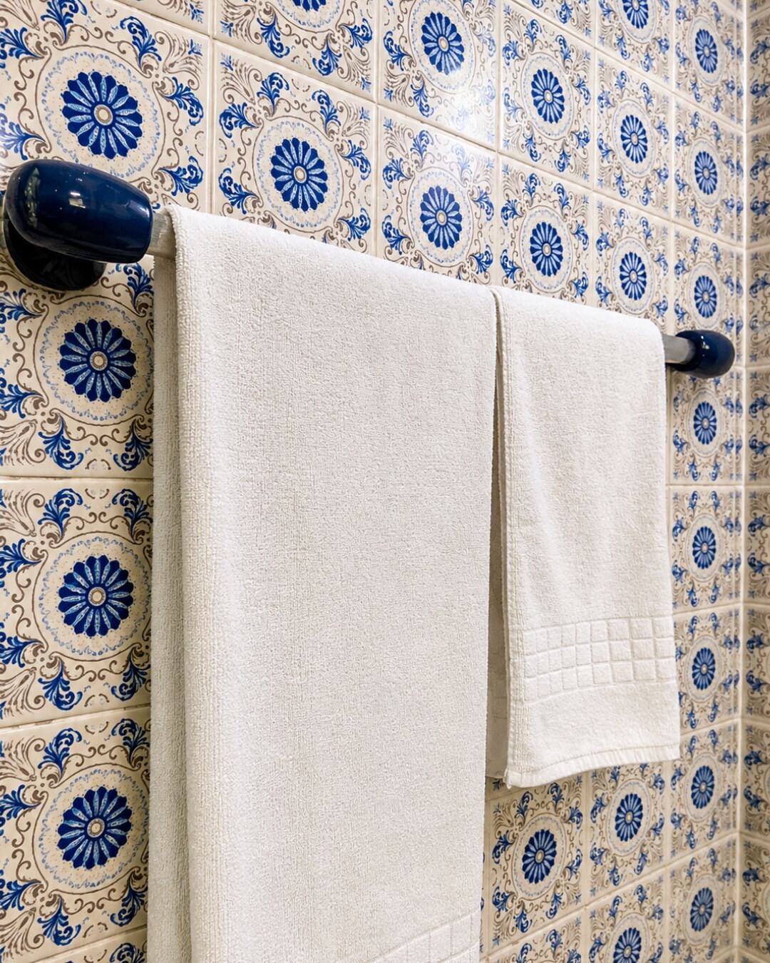 Un baño con baldosas estampadas y dos toallas colgadas en un perchero.