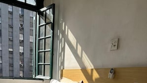 Ein Hotelzimmer mit zwei Betten, einem hölzernen Kopfteil, einem Telefon und einem Fenster mit Jalousien.