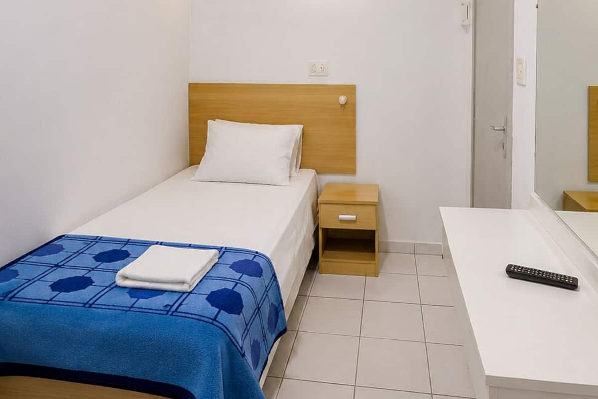 A hotel room with a bed, bedside table, and a mirror.
