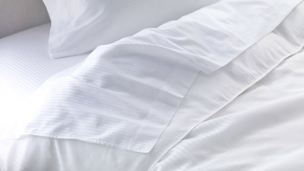 A close-up of white bedding with a smooth texture and a subtle ribbed pattern.