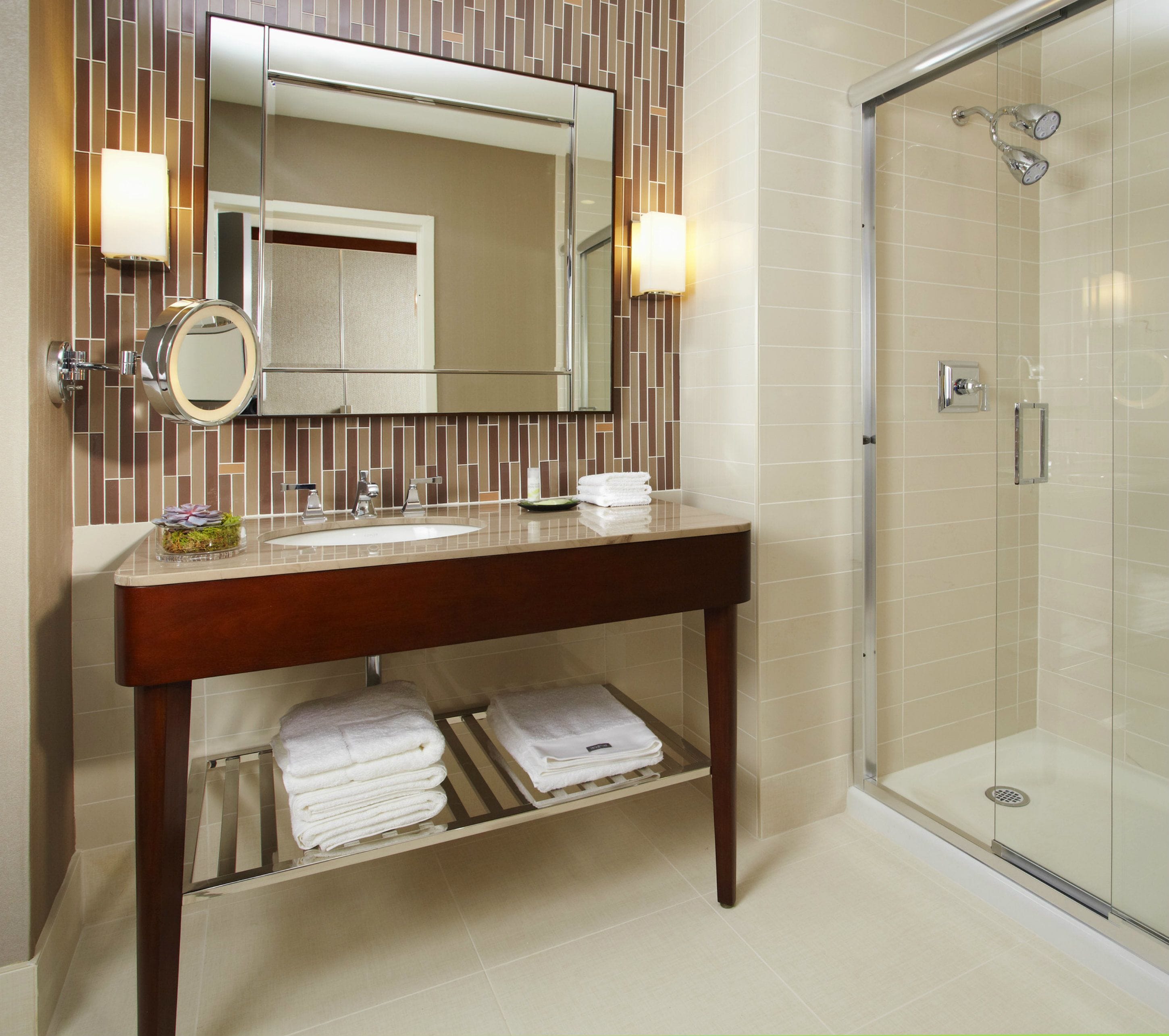 A modern bathroom with a vanity, mirror, and glass-enclosed shower.
