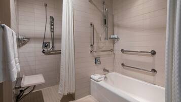 Een moderne badkamer met een inloopdouche, greepstangen, een badkuip en een toilet met een veiligheidsgreep.