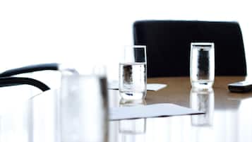 A table with two glasses of water, a smartphone, and a black chair.