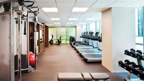 A gym with exercise equipment, treadmills, and a bench.