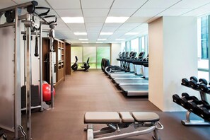 Een sportschool met fitnessapparatuur, loopbanden en een bank.