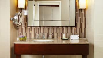 Un baño con tocador de madera, un espejo y un perchero para toallas.
