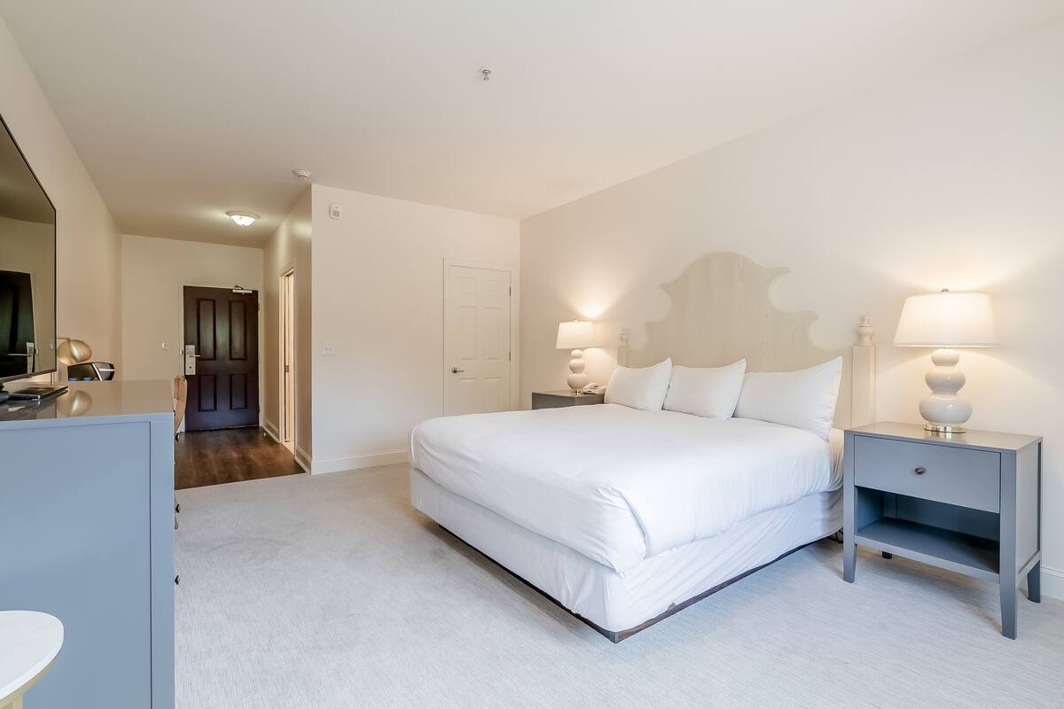 A bedroom with a bed, bedside tables, and a mirror.