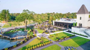 A landscaped courtyard with a fountain, seating areas, and a building with a tower. - Chateau Renault (Egg Harbor City)