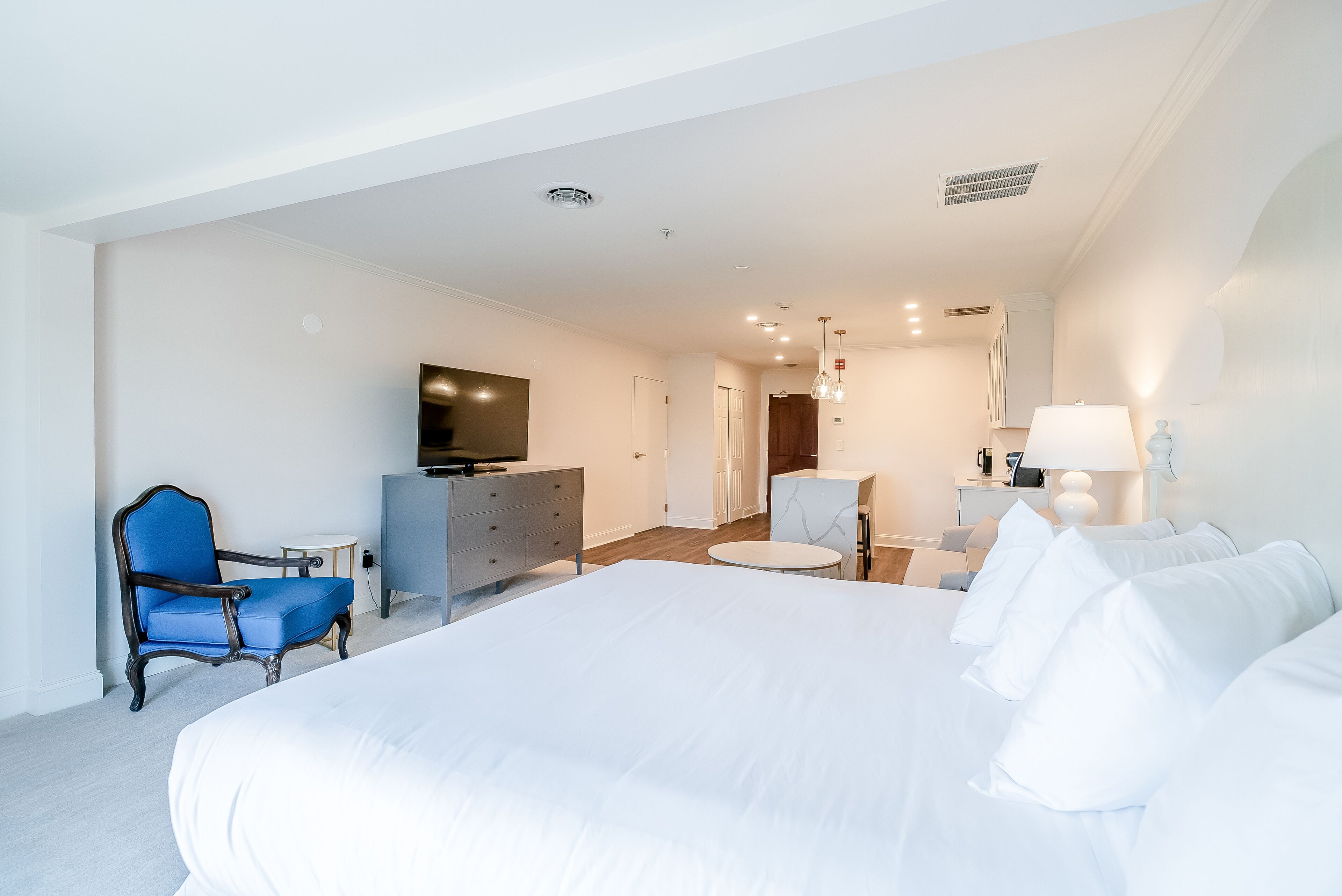 A modern hotel room with a large bed, a television, a desk, and a chair.