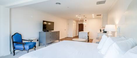 A modern hotel room with a large bed, a television, a desk, and a chair.
