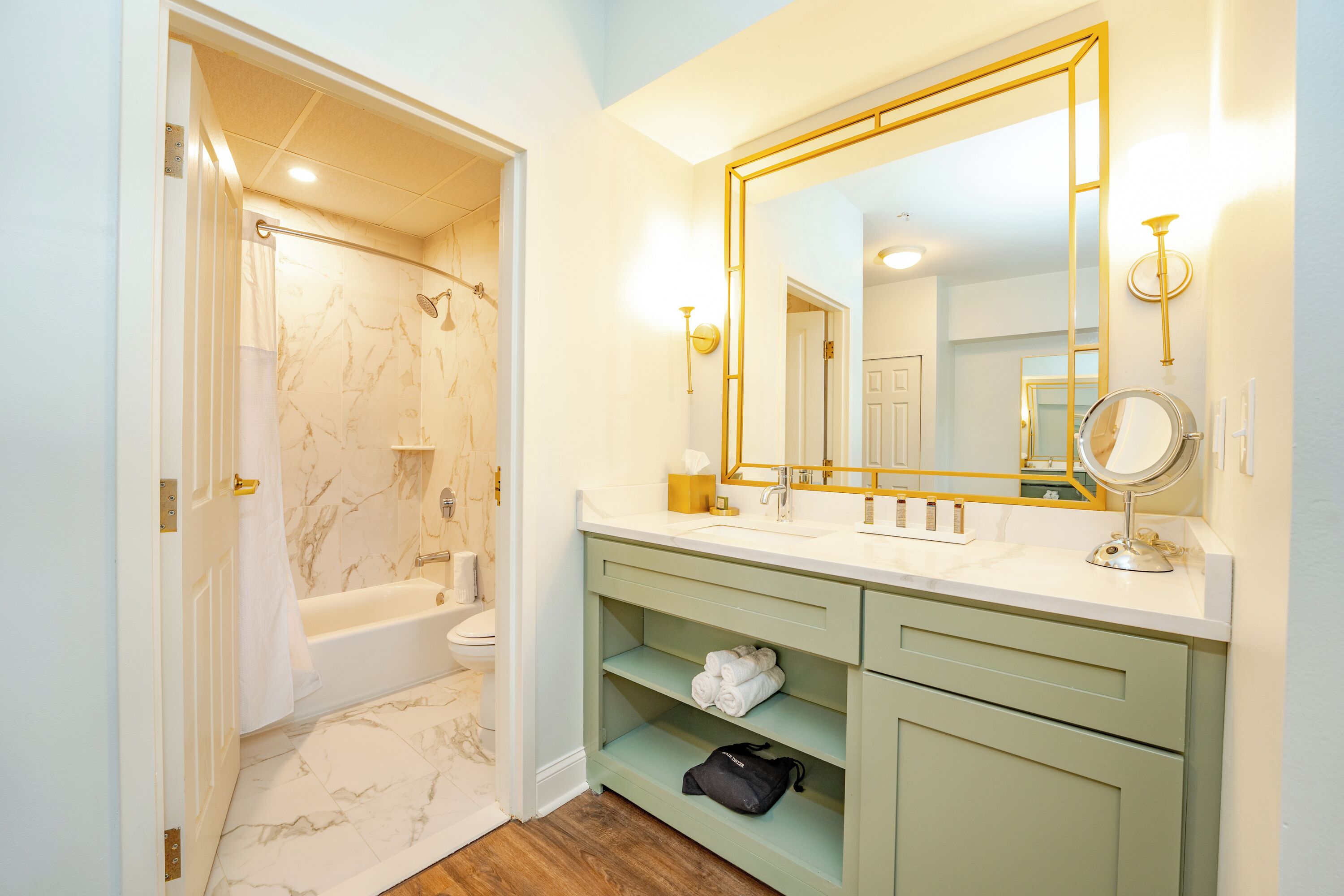 Un bagno con vasca, water, lavabo e mobile contenitore con uno specchio grande.