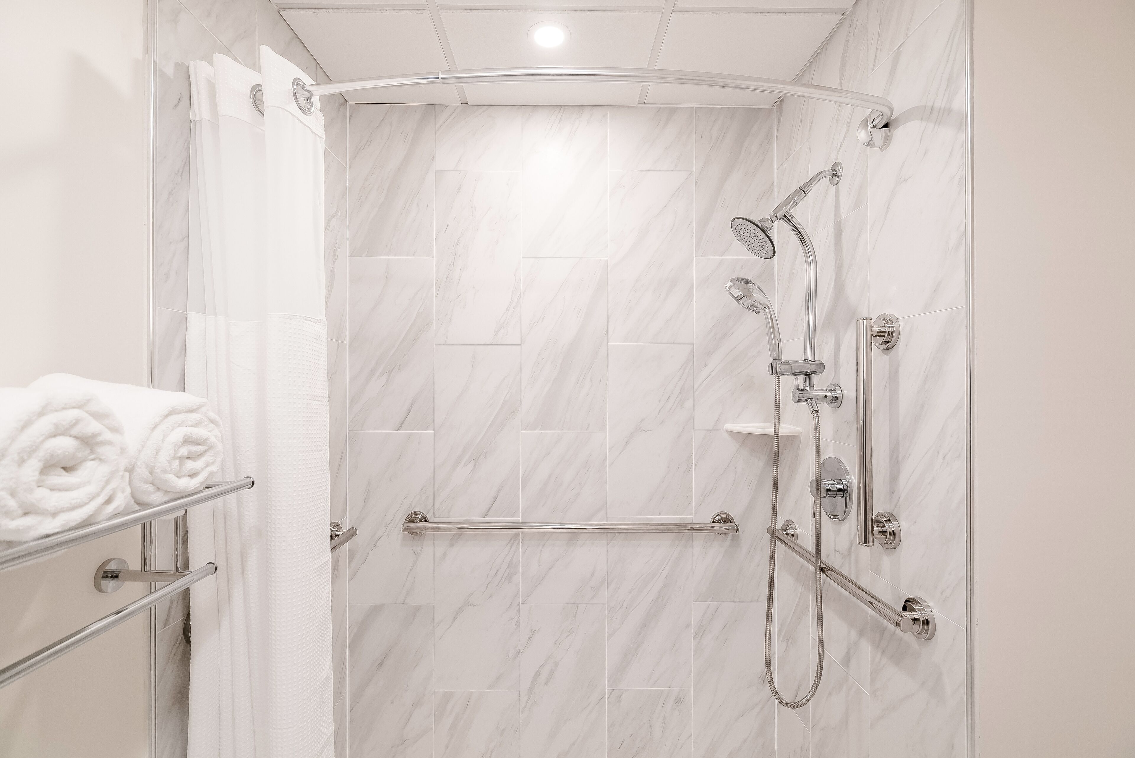 A modern bathroom with a shower, a towel rack, and a glass door.