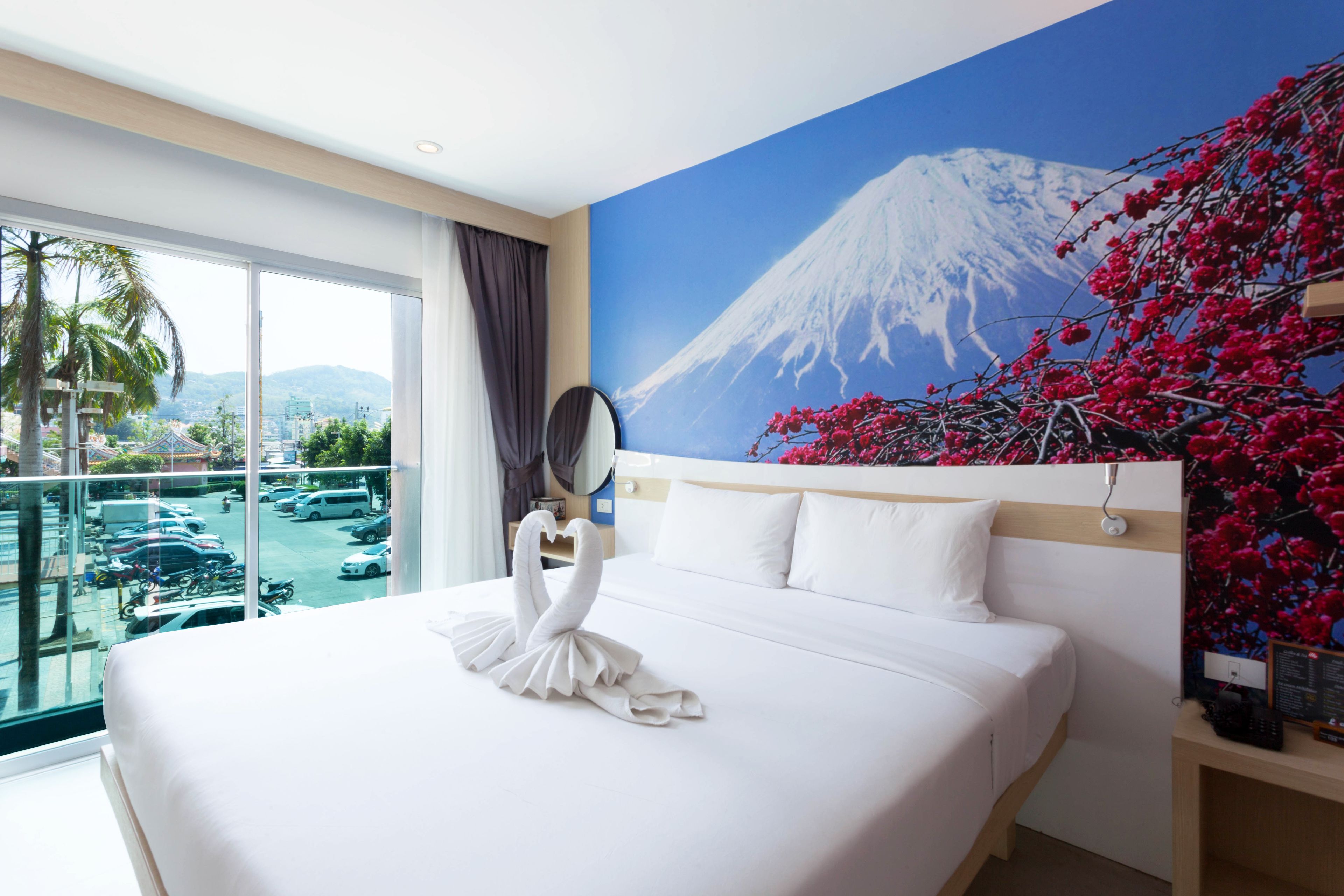 Une chambre d’hôtel avec un grand lit, une vue sur une piscine et un paysage de montagne représenté sur le mur.