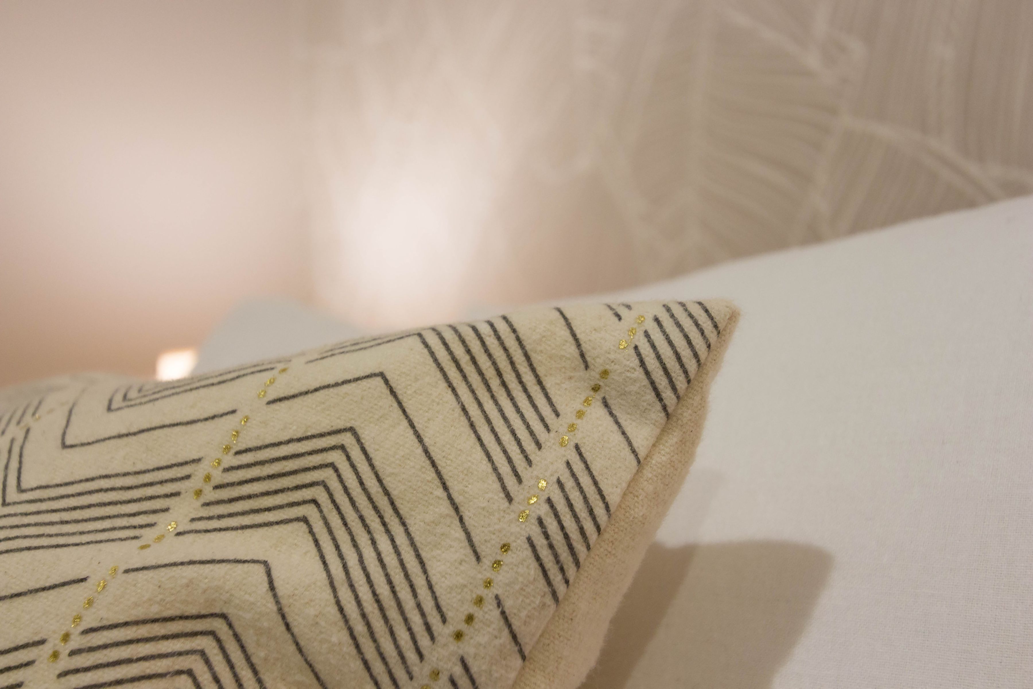 Un almohadón con diseño geométrico y pequeños detalles decorativos.