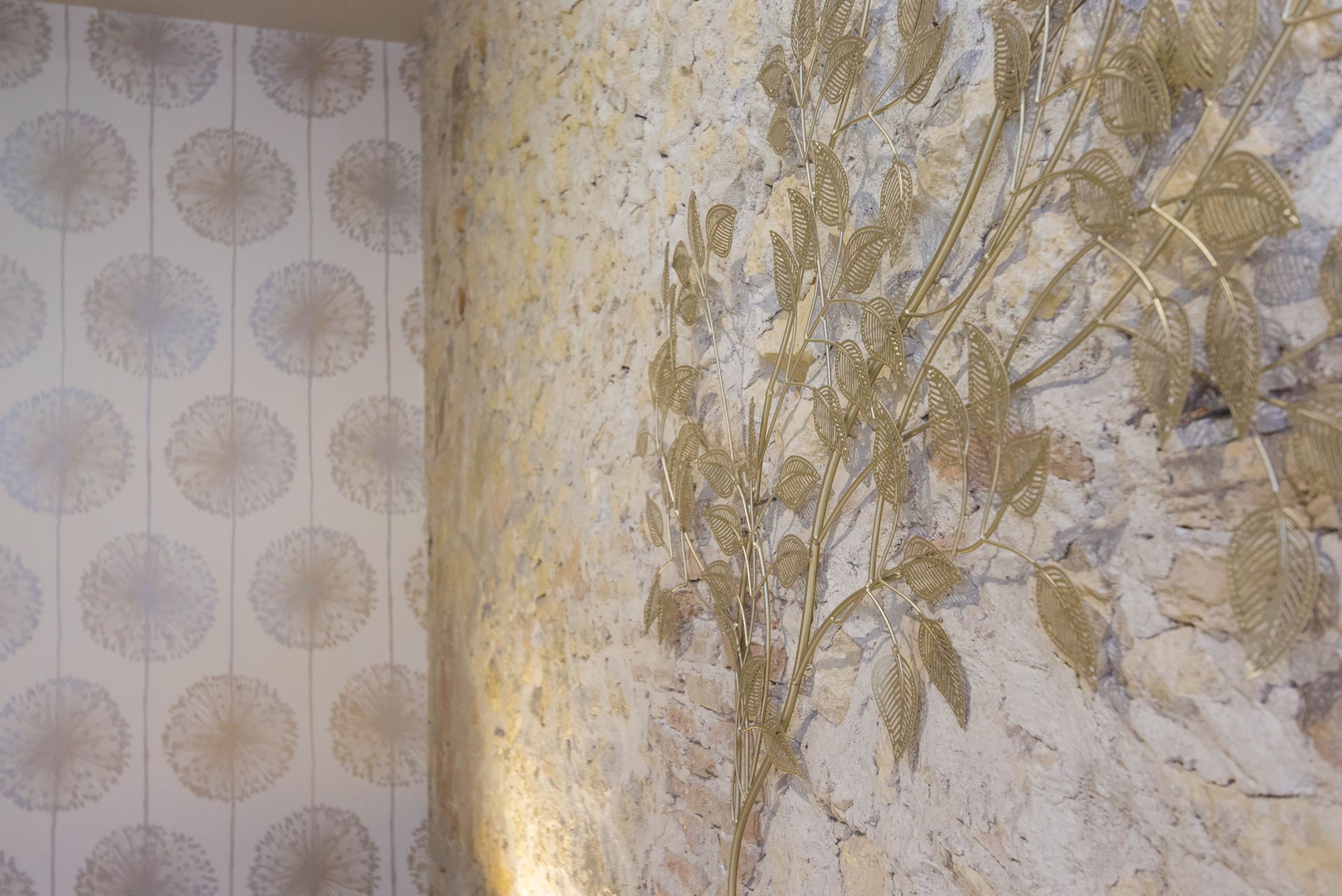 A wall with a circular pattern wallpaper and a metallic plant decoration.