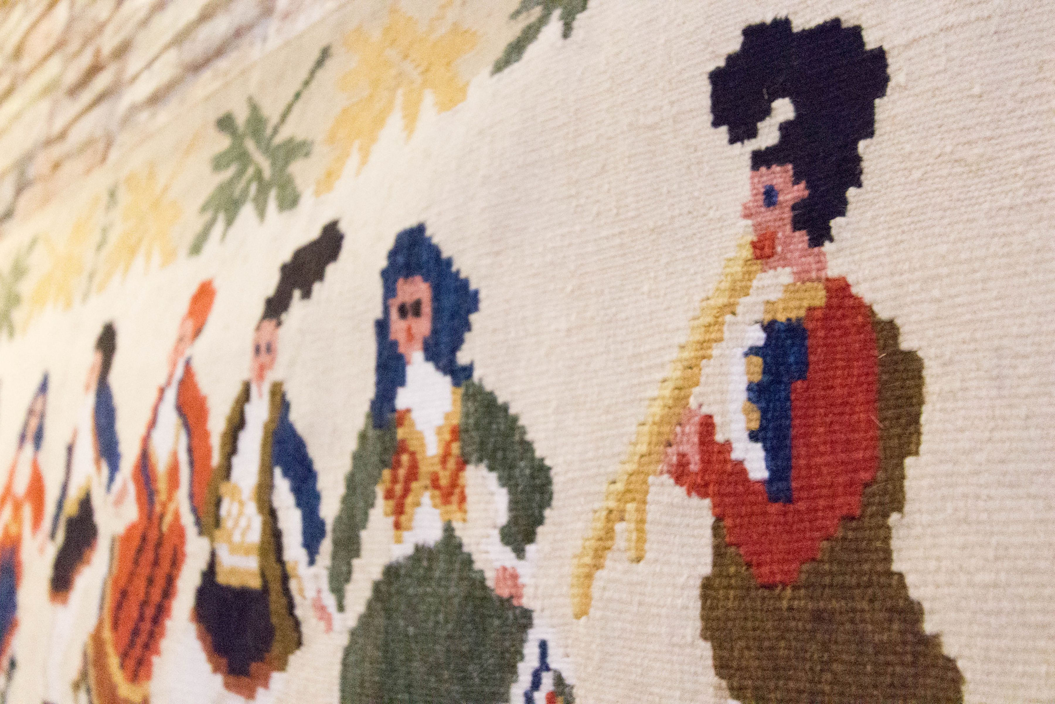 A close-up of a textile with embroidered figures.