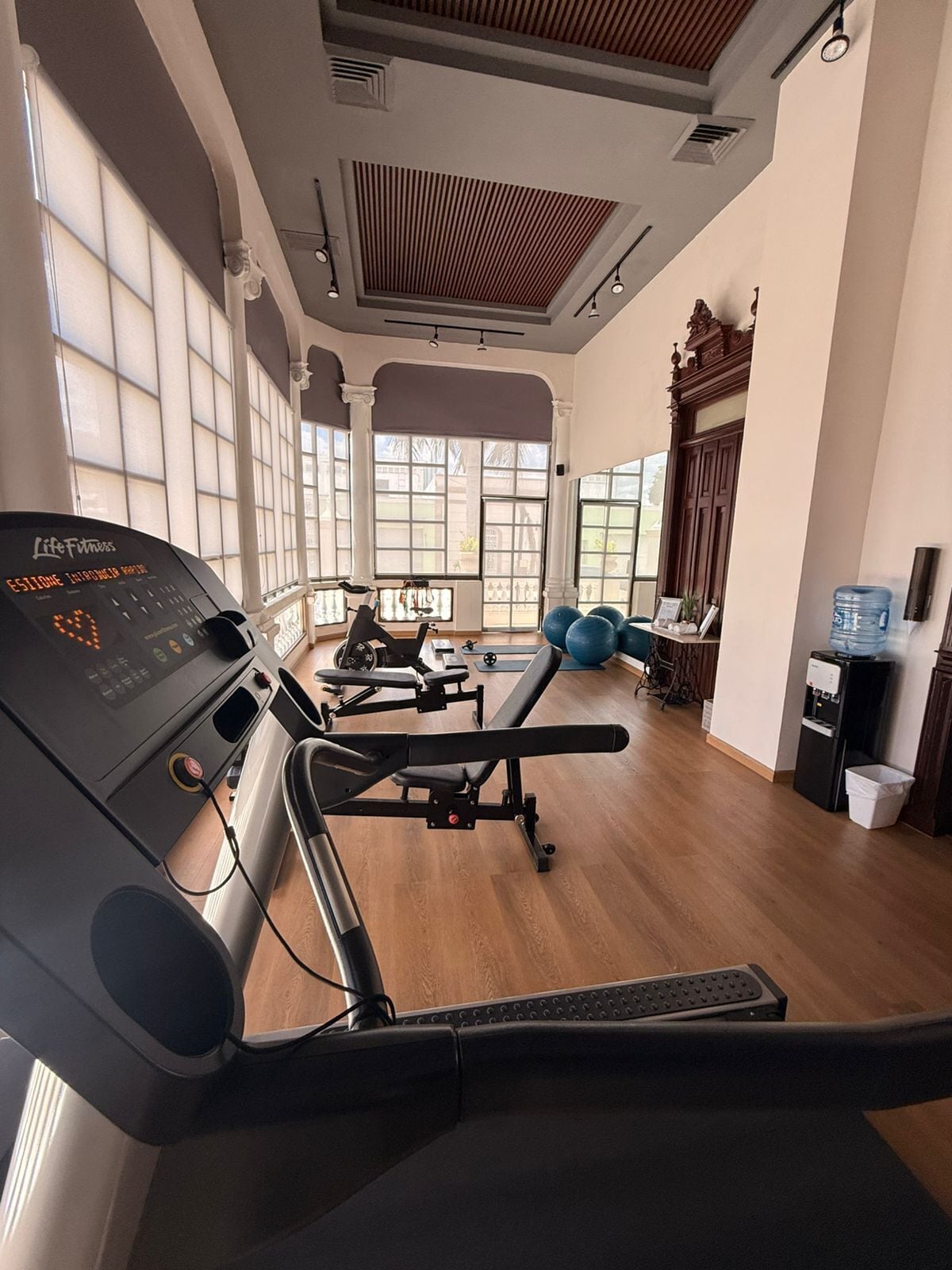 Un gimnasio con cinta de correr, pesas y pelotas de ejercicio.