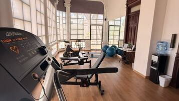 Un gimnasio con cinta de correr, pesas y pelotas de ejercicio.