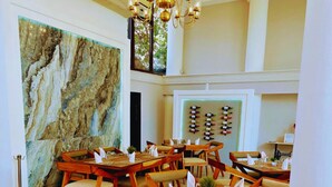 A dining area with wooden tables and chairs, a chandelier, and a wall with wine bottles. - Hotel Residencial (Mérida)