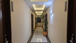 A hallway with a marble floor, recessed lighting, and potted plants. - Hotel Residencial (Mérida)