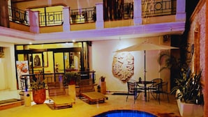 A multi-level indoor pool area with a central pool, lounge chairs, and tables. - Hotel Residencial (Mérida)